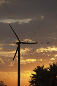 Silhouetted Wind Turbine Over Dramatic Sunset Sky and Clouds.