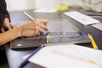 Woman drawing sketches on computer in fashion design studio