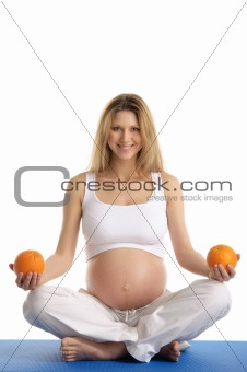 Pregnant woman practicing yoga with oranges