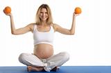 Pregnant woman practicing yoga with oranges