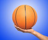 Basketball in hand over blue background