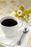 cup of black coffee and flowers on a vintage background