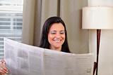 Woman smiling and reading a newspaper