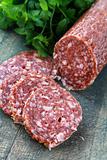 Fresh sausage, salami and parsley on a wooden board
