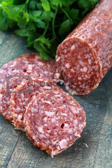 Fresh sausage, salami and parsley on a wooden board