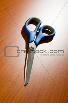 Office scissors against wooden background