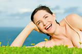 Beautiful happy laughing woman lying in green grass