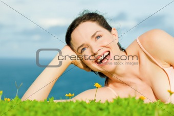 Beautiful happy laughing woman lying in green grass