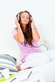 Pretty woman relaxing on couch and listening music in headphones
