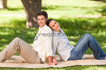 Lovers sitting back to back in the park