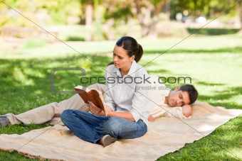 Woman reading while her husband is sleeping