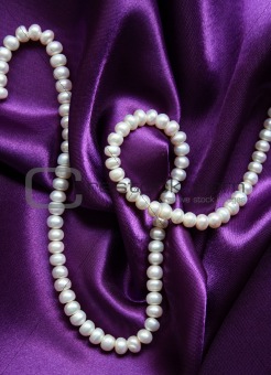 White pearls on a lilac silk background 