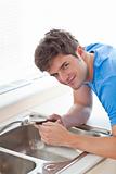 Confident man repairing his sink in the kitchen