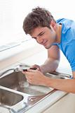 Assertive man repairing his sink in the kitchen