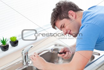 Self-assured man repairing his sink in the kitchen
