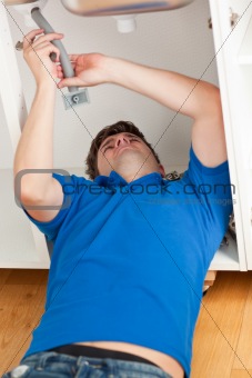 Positive man repairing his sink in the kitchen