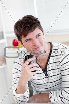Charismatic young man drinking coffee in the kitchen