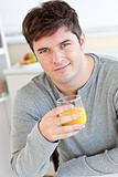 Attractive young man drinking orange juice in the kitchen