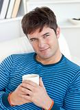 happy man lying on the sofa with a cup of tea in the living-room