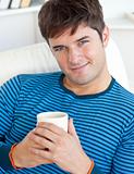 happy man resting on his couch with a cup of coffee