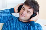 peaceful man listening music holding his earphones lying on the 
