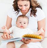 Bright mother showing images in a book to her cute little son