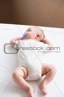 Portrait of a sweet baby with a pacifier sleeping on the sofa in