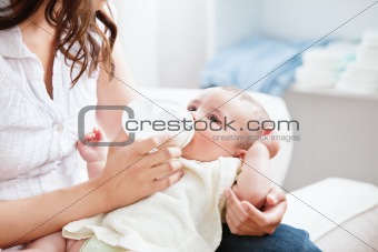 Bright mother feeding her adorable son in the kitchen