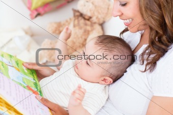 Joyful mother showing images in a book to her cute little son