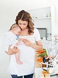 Caring mother preparing food for her adorable baby in the kitchen