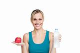 healthy woman holding an apple and a bottle of water against a w