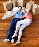 happy couple lying on the floor in their new house doing thumbs-