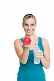 Young smiling woman holding bottle of water and apple
