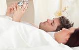 Young caucasian couple holding an alarm clock in bed before slee