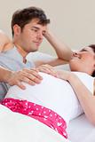 Joyful caucasian pregnant woman lying on bed with her husband