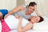 Happy caucasian pregnant woman lying on bed with her husband