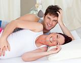Laughing caucasian pregnant woman lying on bed with her husband