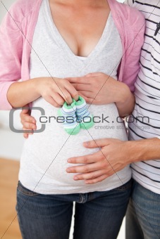 Close-up of a caucasian pregnant woman holding baby shoes and of