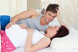Delighted caucasian pregnant woman lying on bed with her husband