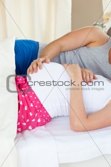 Close-up of a caucasian pregnant woman lying on bed with her hus