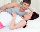 Worried pregnant woman lying on bed with her husband