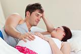 Joyful pregnant woman lying on bed with her husband