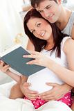 Portrait of a pretty pregnant woman and of her husband reading a
