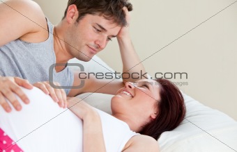 Portrait of a pregnant woman and of her husband lying on the bed
