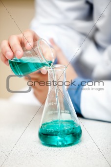Male chemist pouring a blue liquid