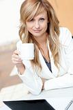 Bright businesswoman holding a cup of coffee in front of her lap