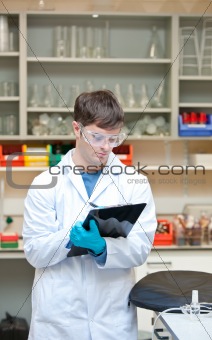 Concentrated male scientist writing on a clipboard