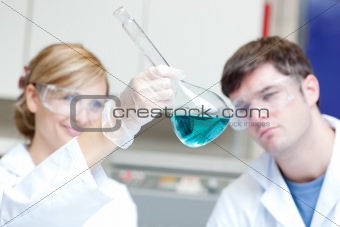 Two serious scientists looking at a blue liquid