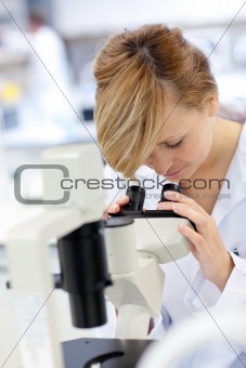 Serious female scientist using a microscope