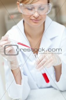Close-up of a concentrated female scientist putting liquid in a 